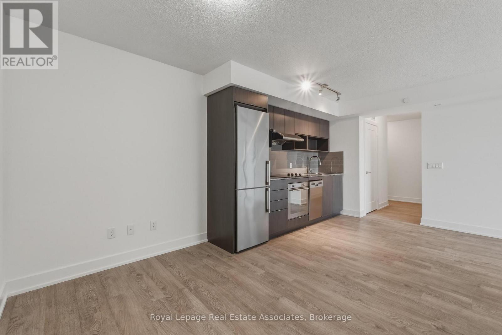 A kitchen with a refrigerator, oven, and microwave in a white room.