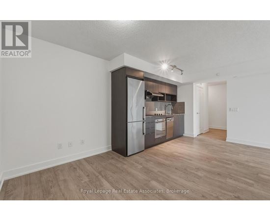 A kitchen with a refrigerator, oven, and microwave in a white room.