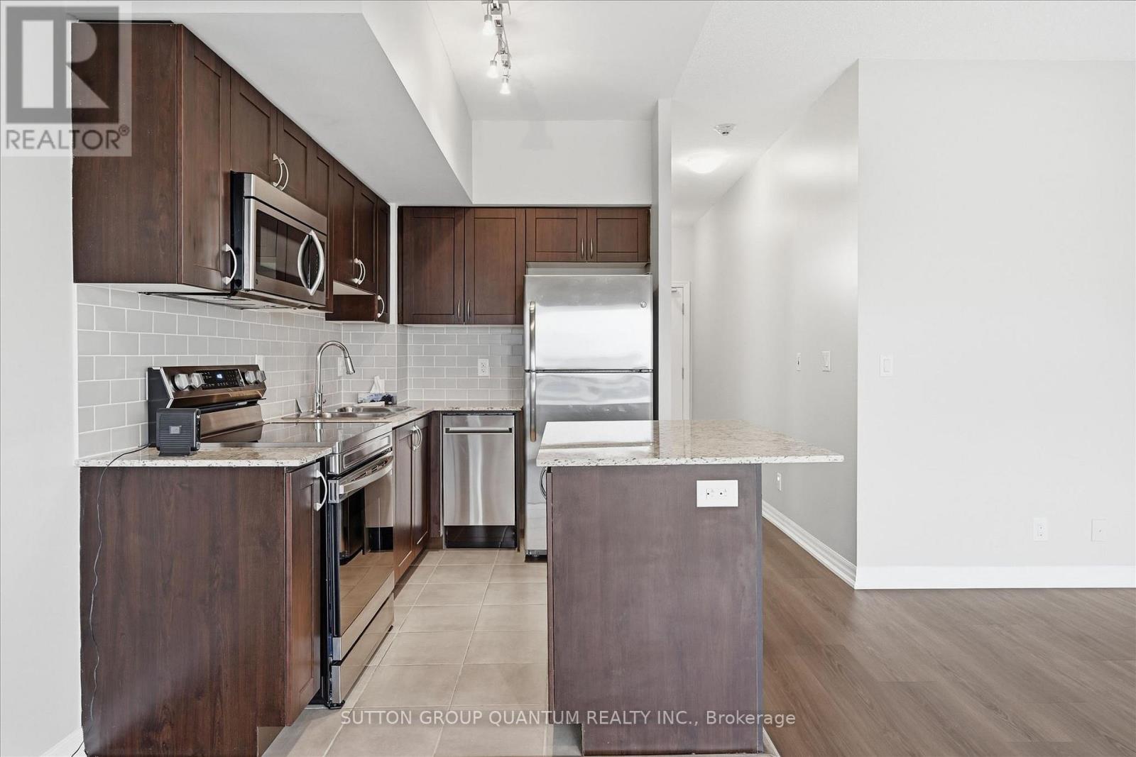 A kitchen with dark wood cabinets and stainless steel appliances.
