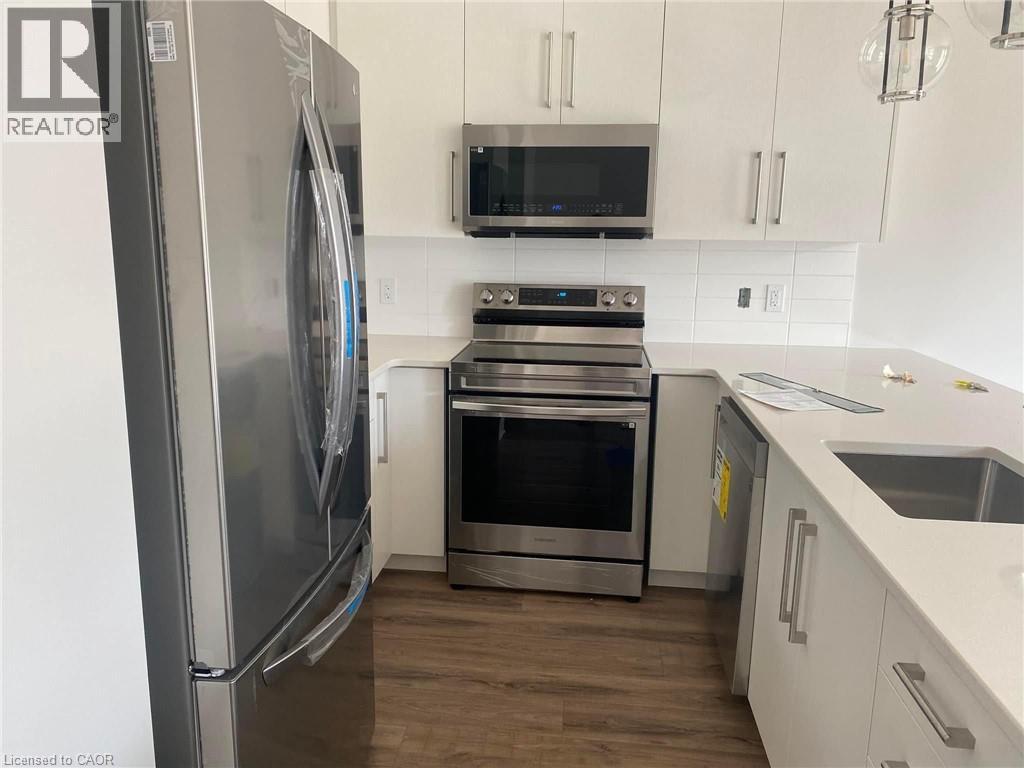 A modern kitchen with a stainless steel refrigerator and oven.