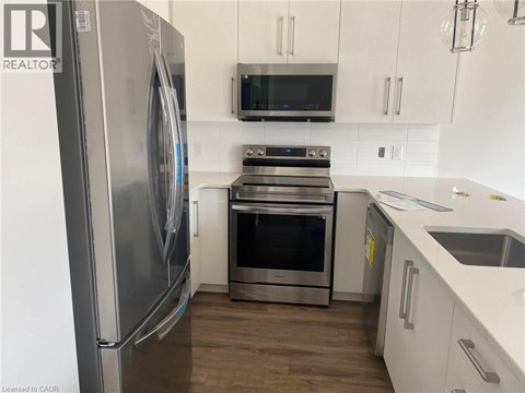 A modern kitchen with a stainless steel refrigerator and oven.