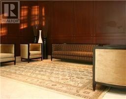 A living room with a brown couch and a rug.