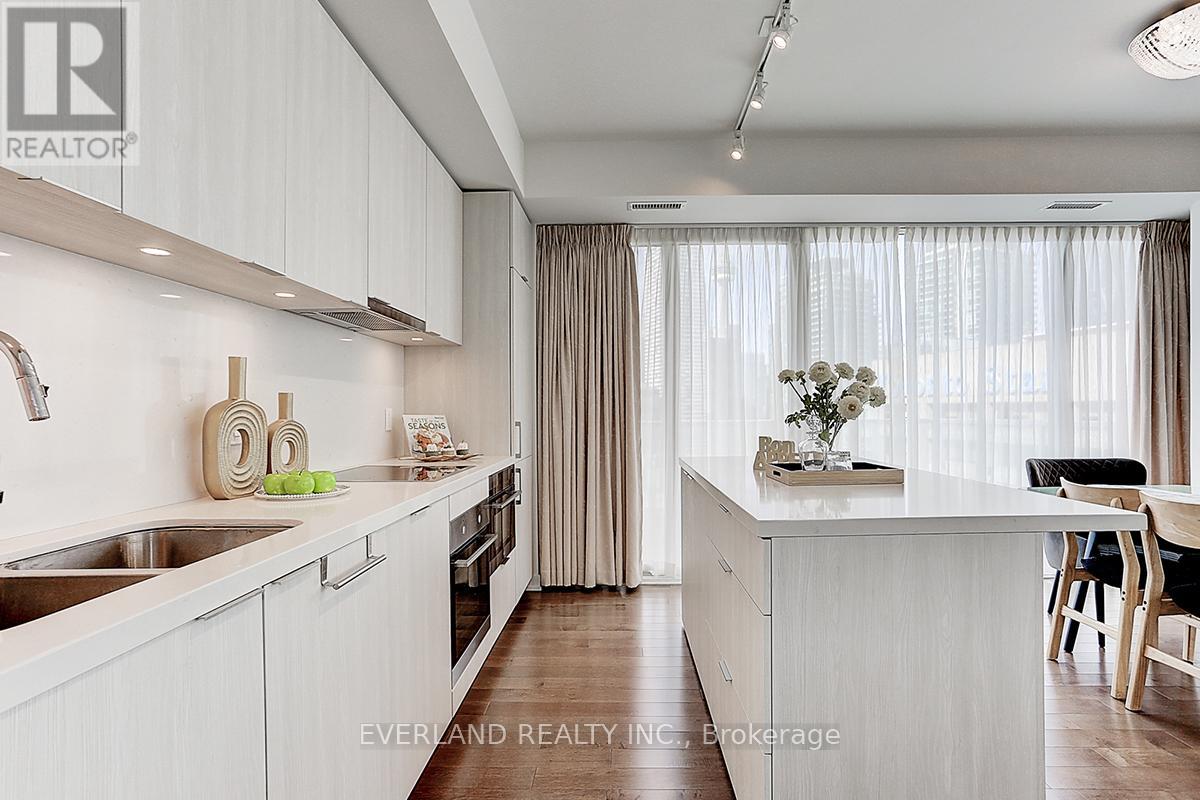A modern kitchen with white cabinets and a wooden floor.