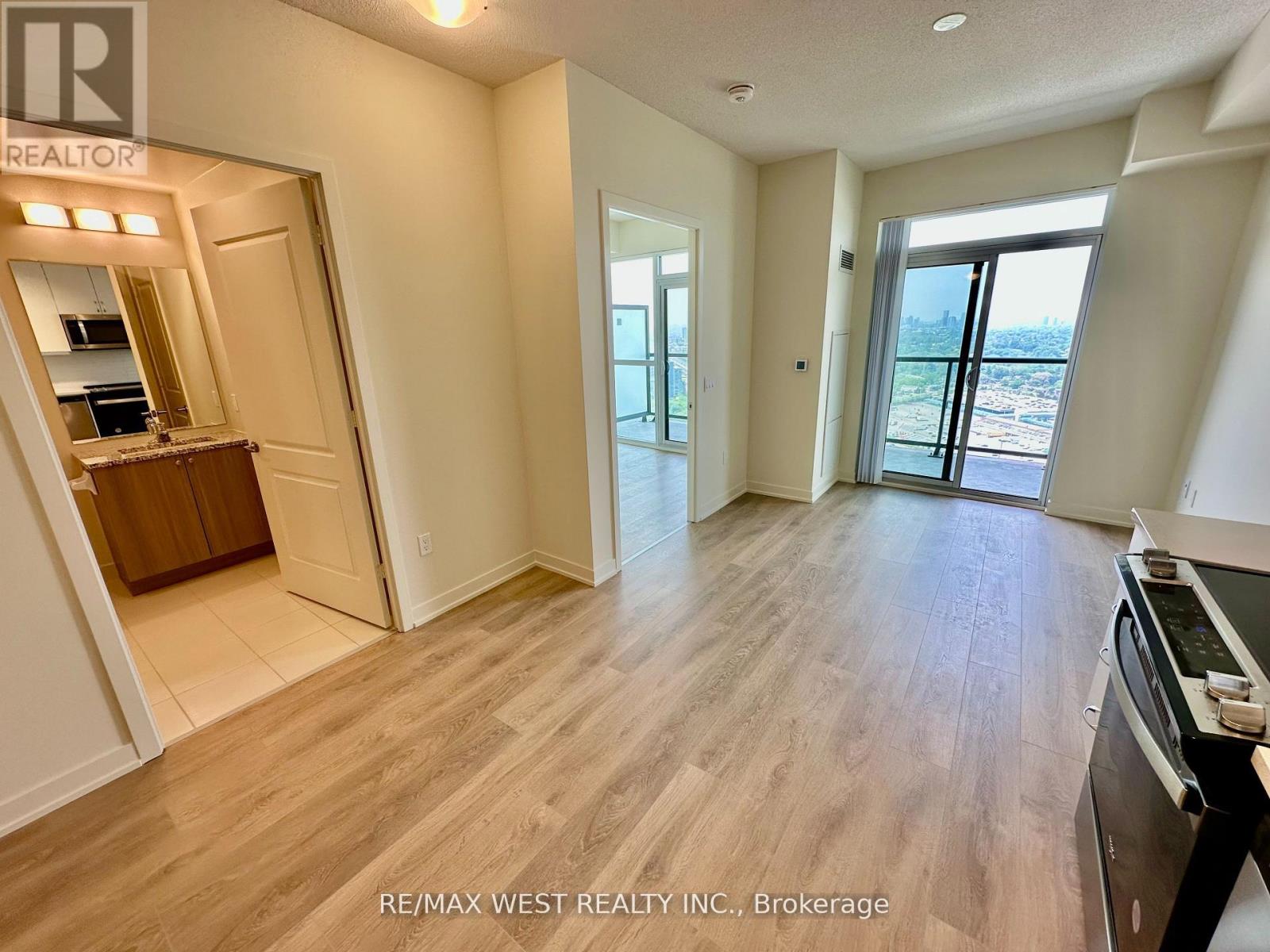 A spacious room with wooden flooring and a large window overlooking a cityscape.
