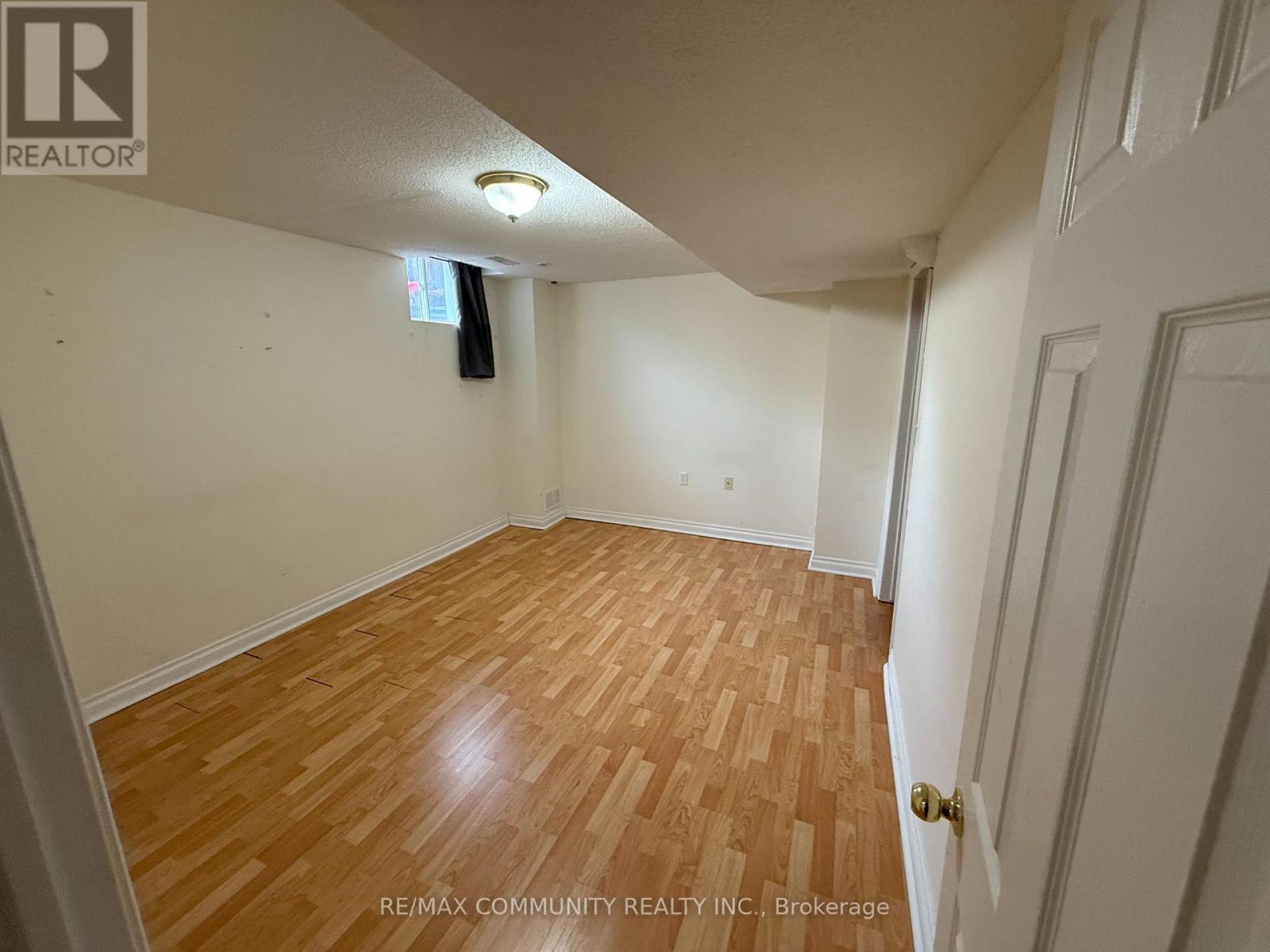 A room with wooden flooring and white walls, with a door on the right side.
