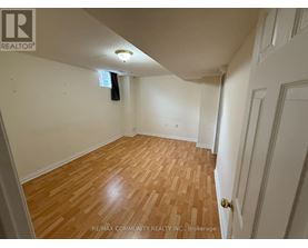 A room with wooden flooring and white walls, with a door on the right side.