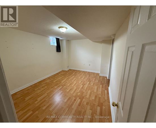 A room with wooden flooring and white walls, with a door on the right side.