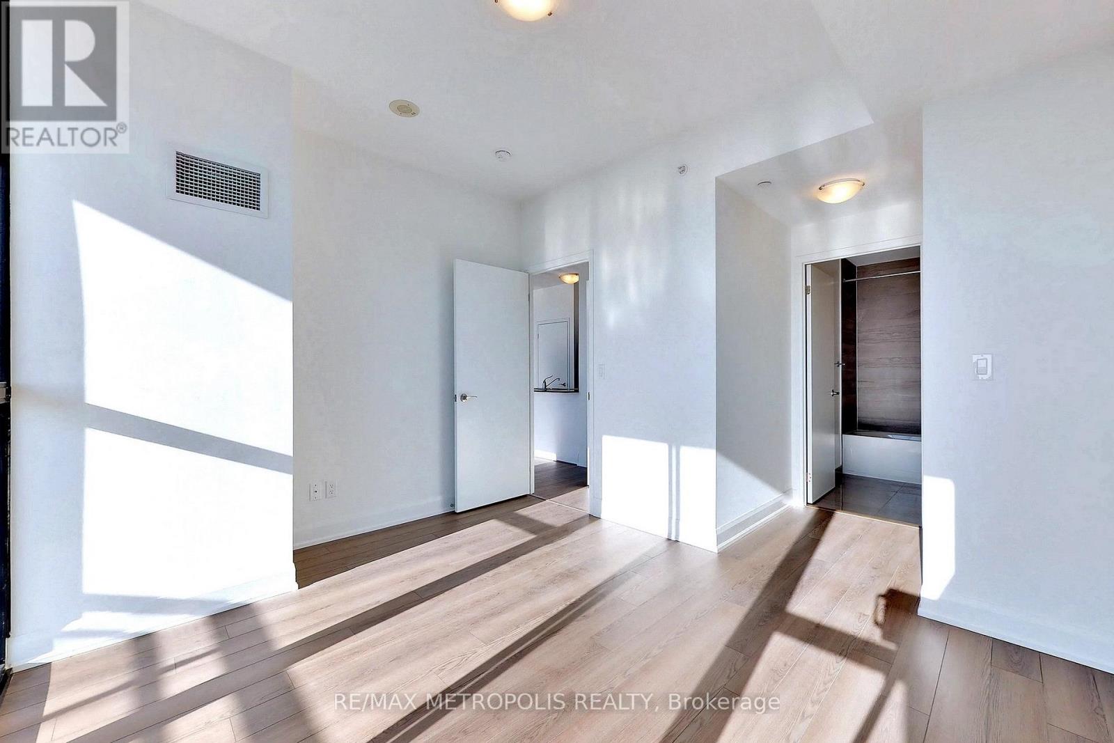 A spacious room with wooden floors and white walls.