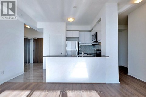 A modern kitchen with white cabinets and a wooden floor.