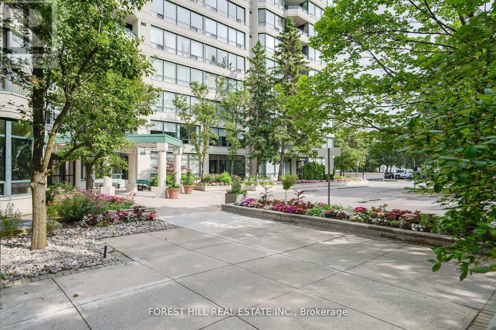 A courtyard with a lot of greenery and a building in the background.