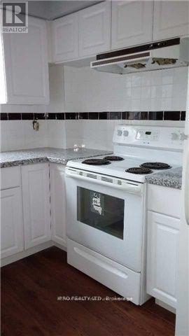 A white stove in a kitchen with white cabinets.