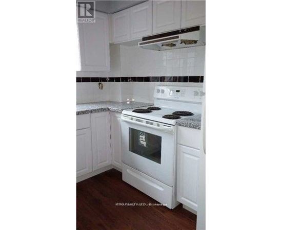 A white stove in a kitchen with white cabinets.