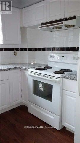 A white stove in a kitchen with white cabinets.
