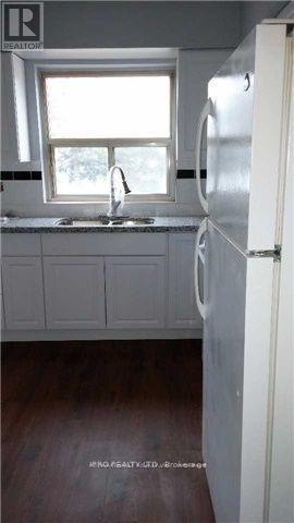 A kitchen with a white refrigerator and a window above the sink.