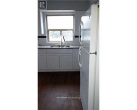 A kitchen with a white refrigerator and a window above the sink.
