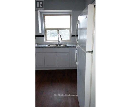 A kitchen with a white refrigerator and a window above the sink.
