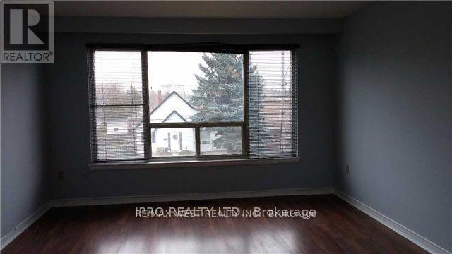 A room with a window showing a view of a house and a tree outside.