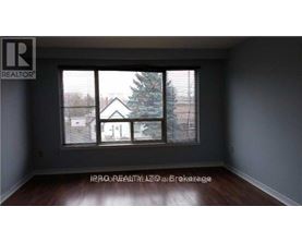 A room with a window showing a view of a house and a tree outside.