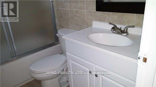 A white toilet sits next to a white sink in a bathroom.
