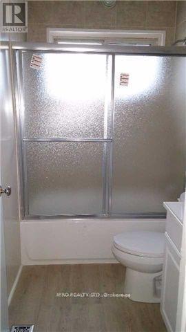 A bathroom with a toilet and a glass door shower.