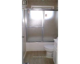 A bathroom with a toilet and a glass door shower.
