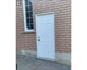 A white door is on the side of a brick building.