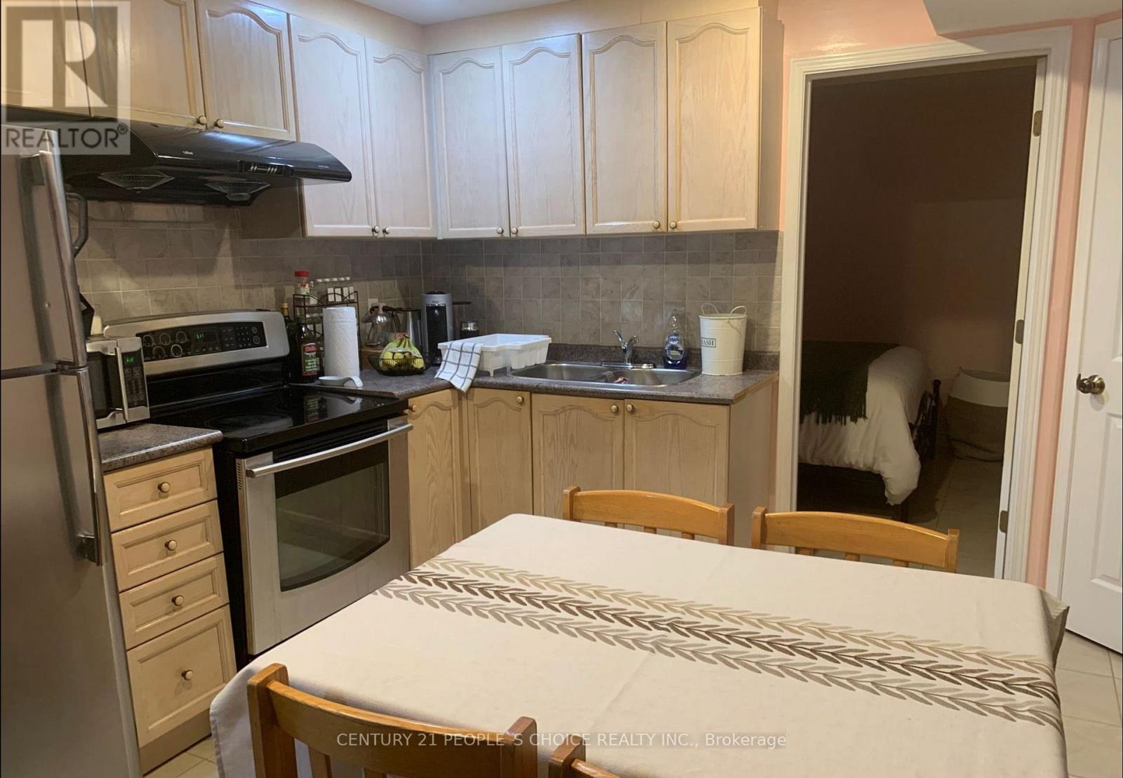 A kitchen with a table and chairs in the foreground and a person in the background.