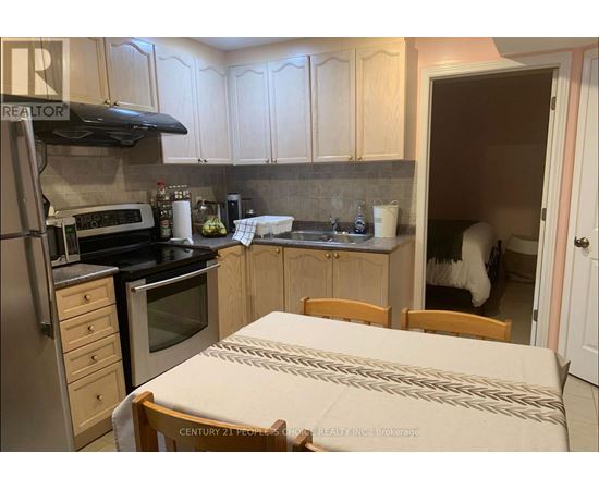 A kitchen with a table and chairs in the foreground and a person in the background.