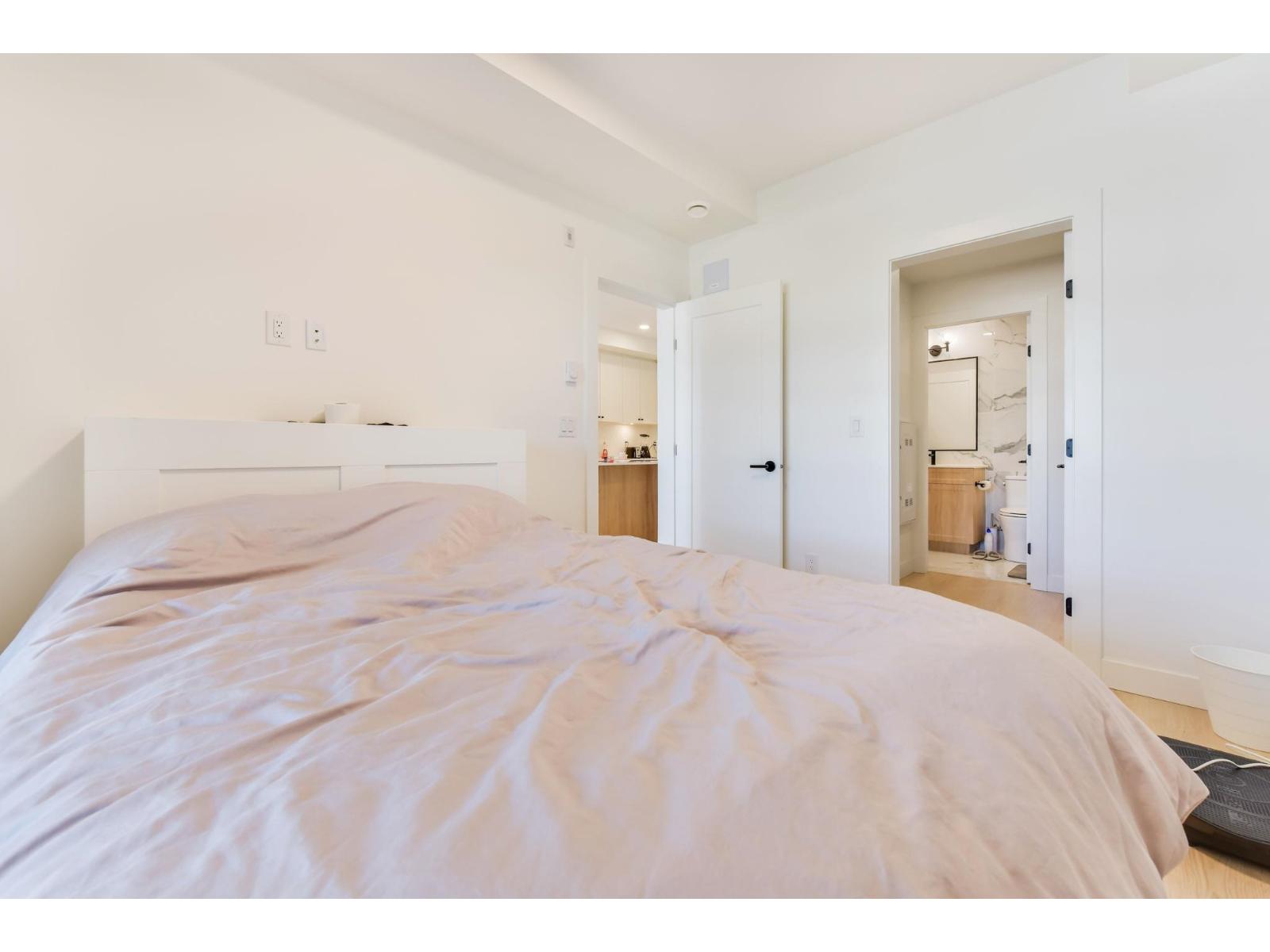 A bedroom with a large bed and a white wall.