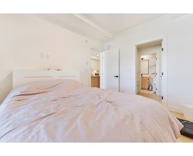 A bedroom with a large bed and a white wall.