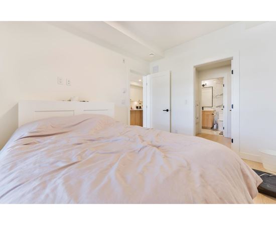 A bedroom with a large bed and a white wall.