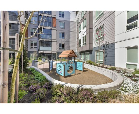 A playground area with a slide and a sign that says "Playground" is surrounded by buildings.