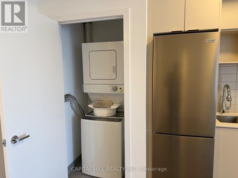 A stainless steel refrigerator in a kitchen with a white door.