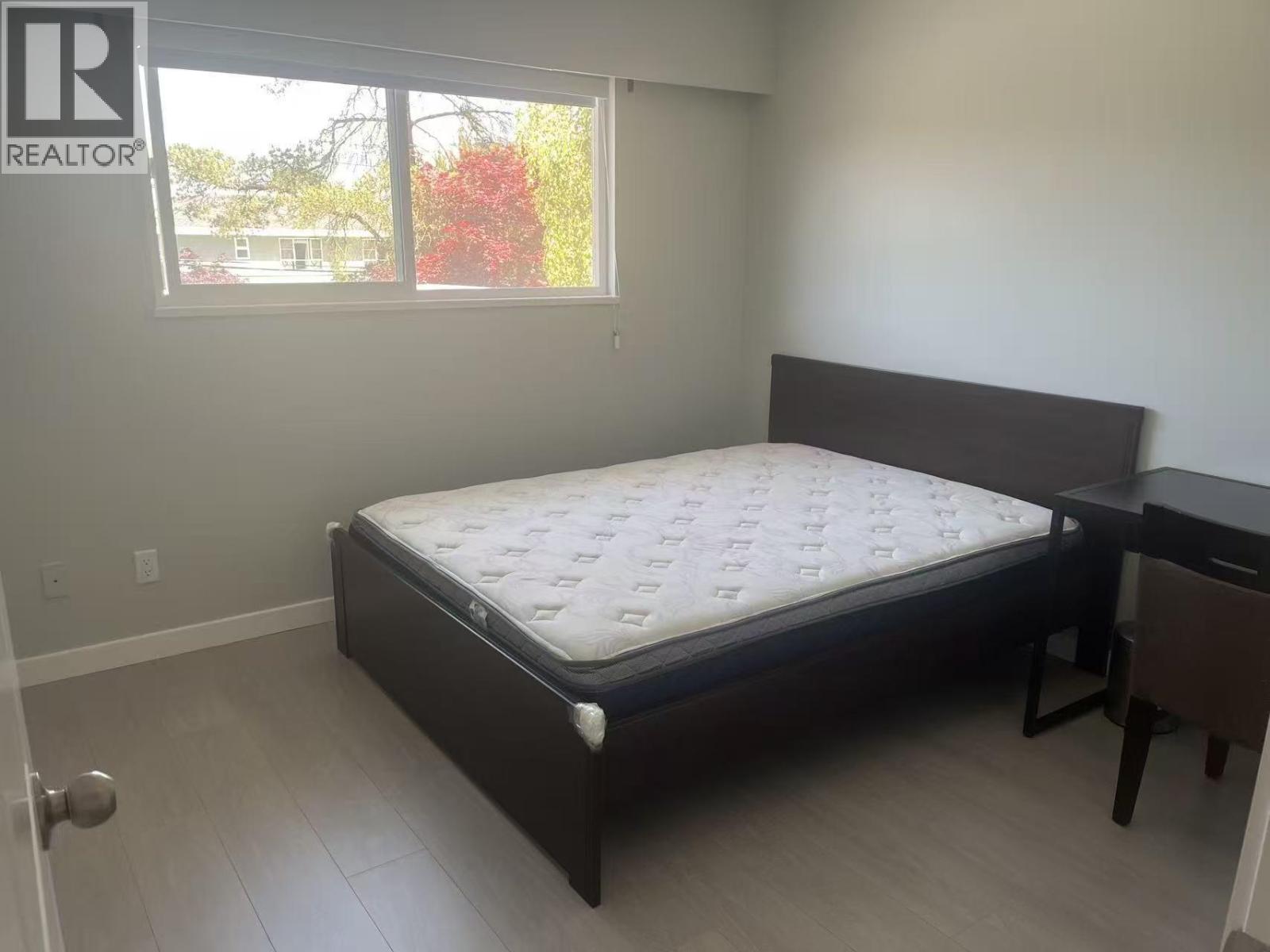 A bedroom with a bed, nightstand, and window.