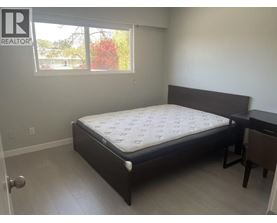 A bedroom with a bed, nightstand, and window.