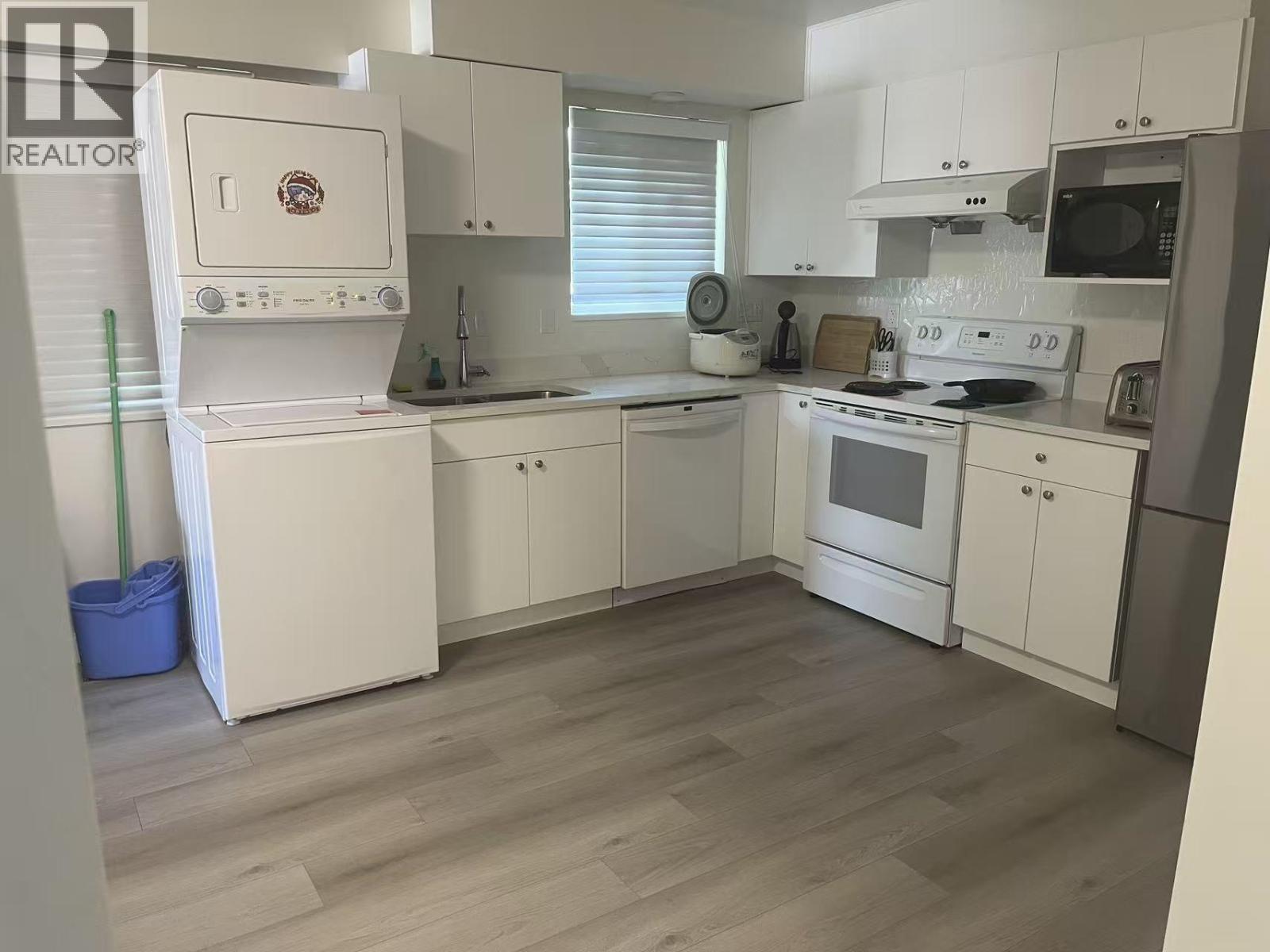 A kitchen with white appliances and cabinets.
