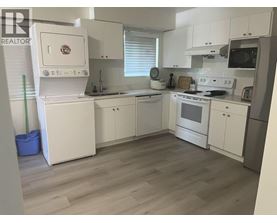 A kitchen with white appliances and cabinets.