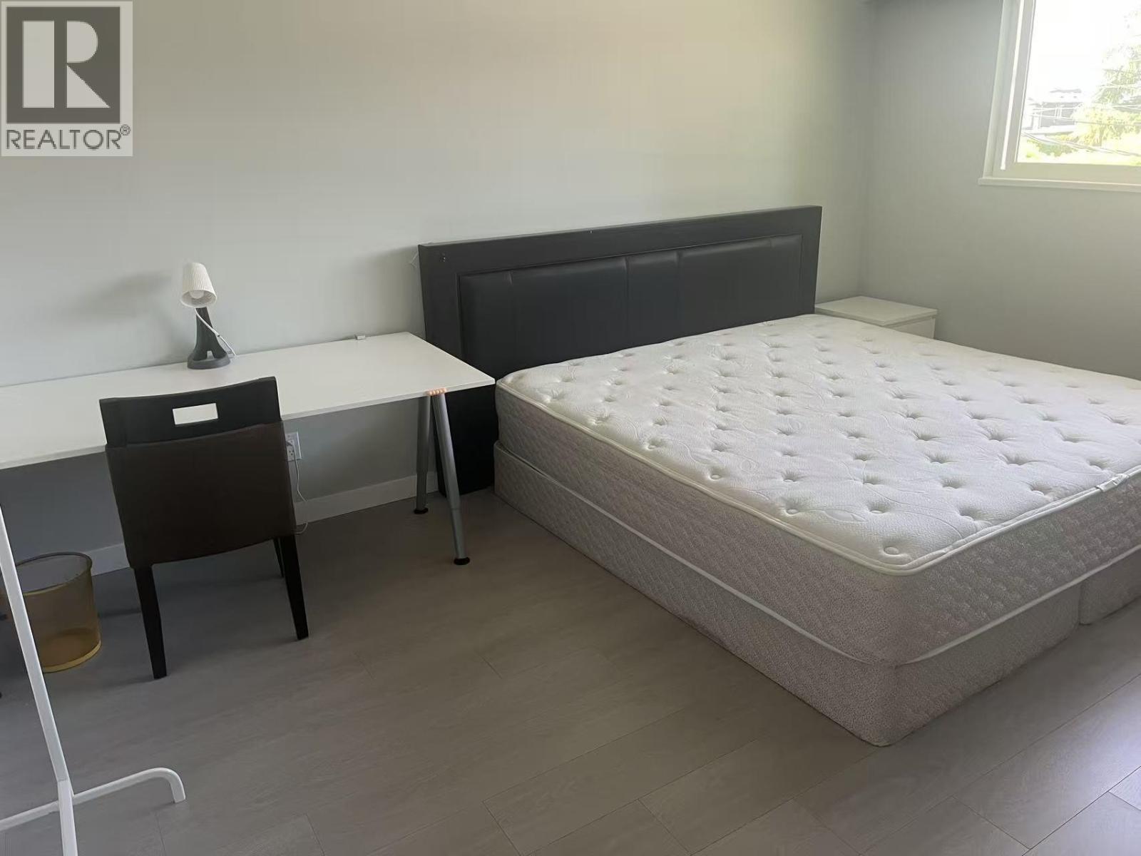 A bedroom with a bed, desk, and chair.