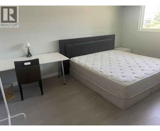 A bedroom with a bed, desk, and chair.