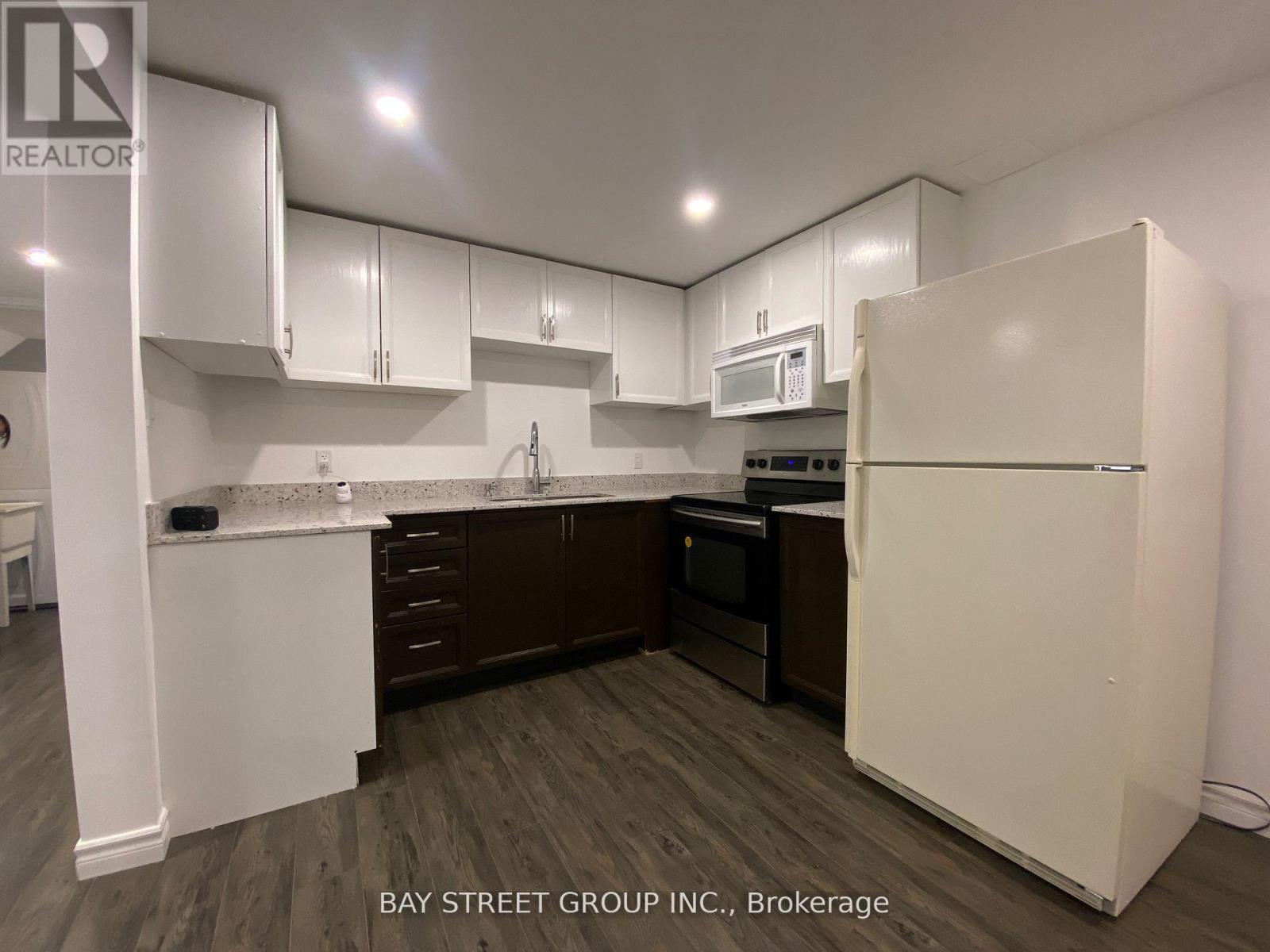 A kitchen with white cabinets and a white refrigerator.