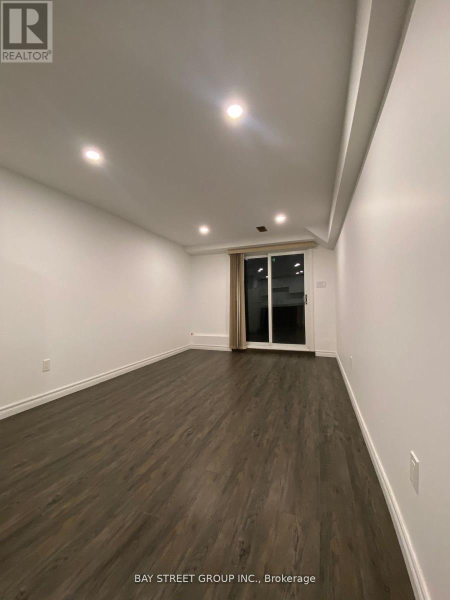 A spacious room with wooden flooring and a slanted ceiling.