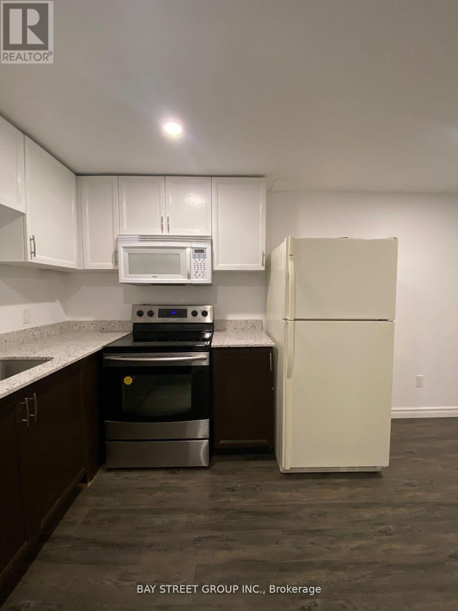 A kitchen with a refrigerator, microwave, oven, and sink.