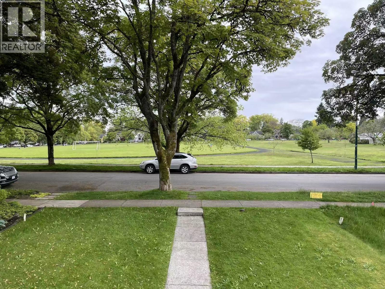 A grassy area with a tree and a sign that says REALTOR.
