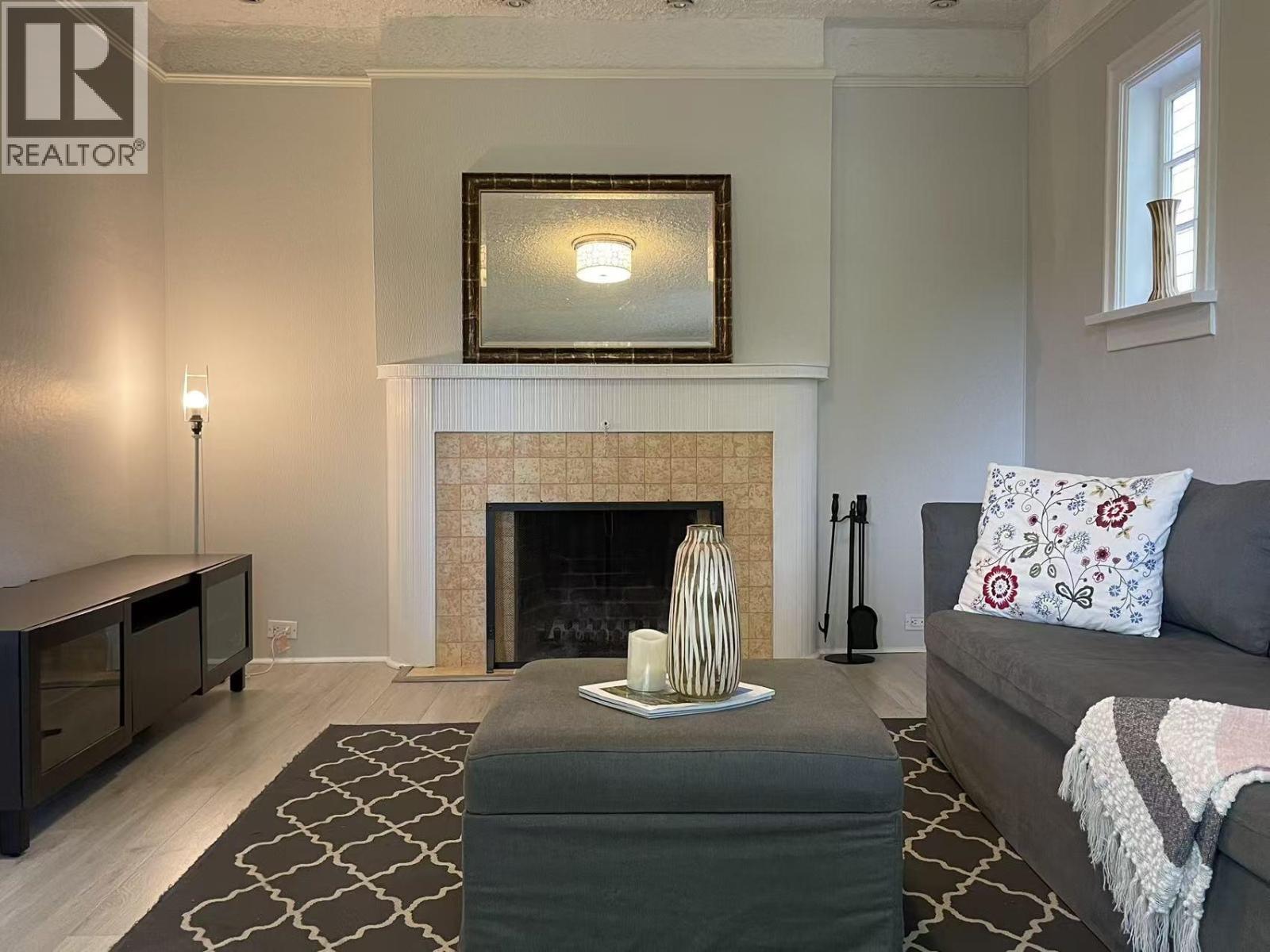 A living room with a fireplace and a grey couch.