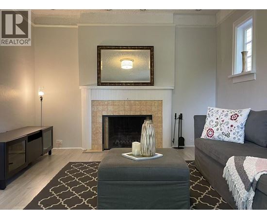 A living room with a fireplace and a grey couch.