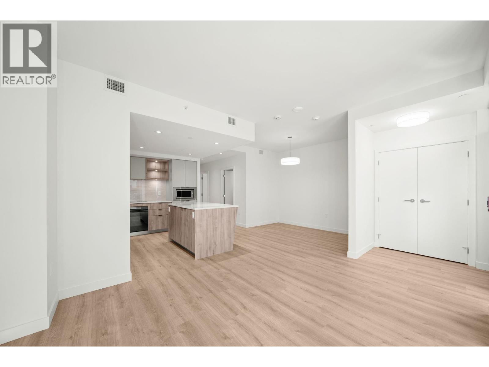 A spacious room with wooden flooring and white walls.