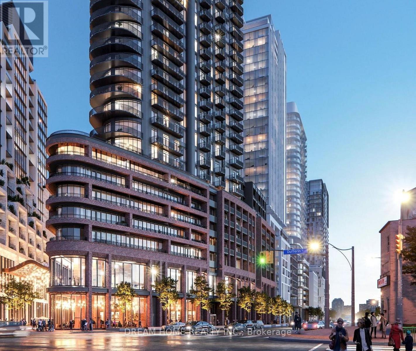 A modern building with a curved glass facade is illuminated at dusk.