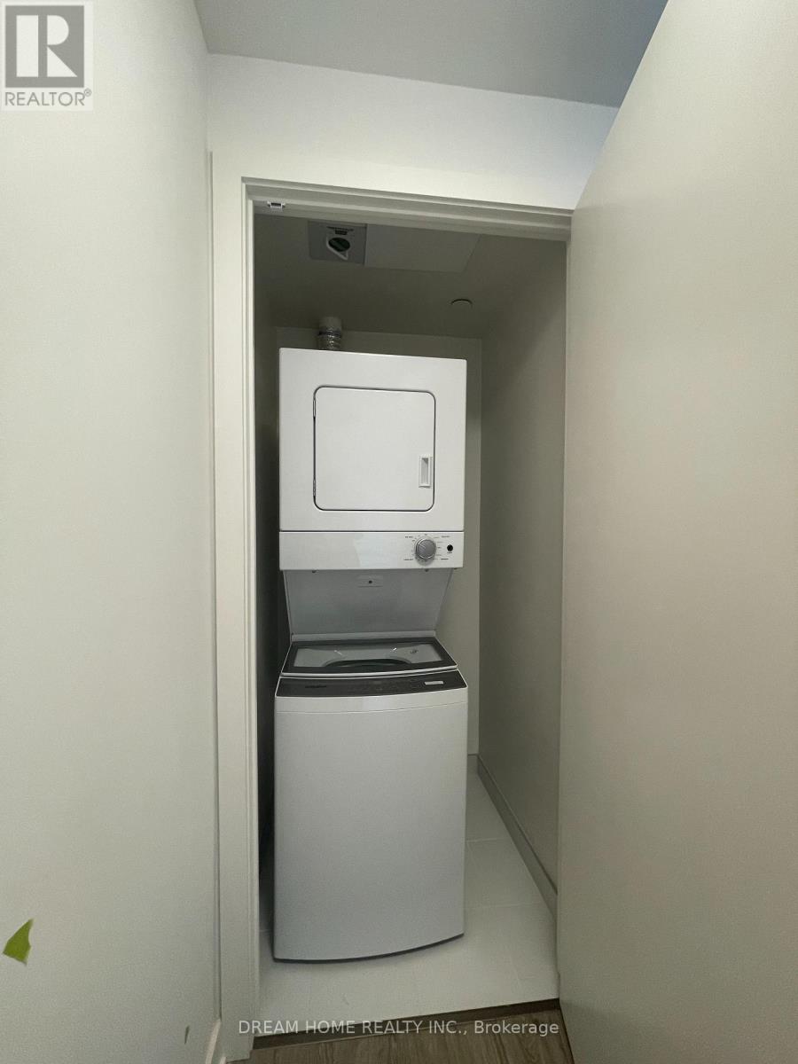 A small white washer and dryer unit in a narrow space.