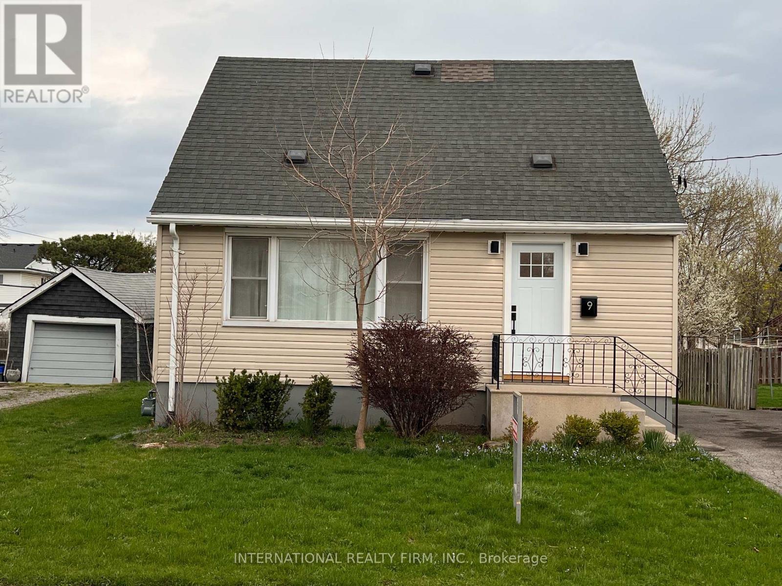 A beige house with a white door and a small tree in front.