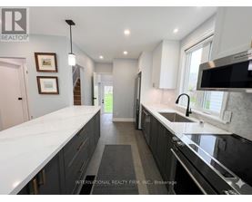 A modern kitchen with dark cabinets and a white countertop.